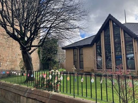 The church from the street in spring, with paper Easter eggs hanging along the railings.