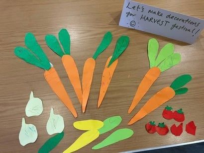 Paper carrots and leaves cut out as decorations for the harvest festival.